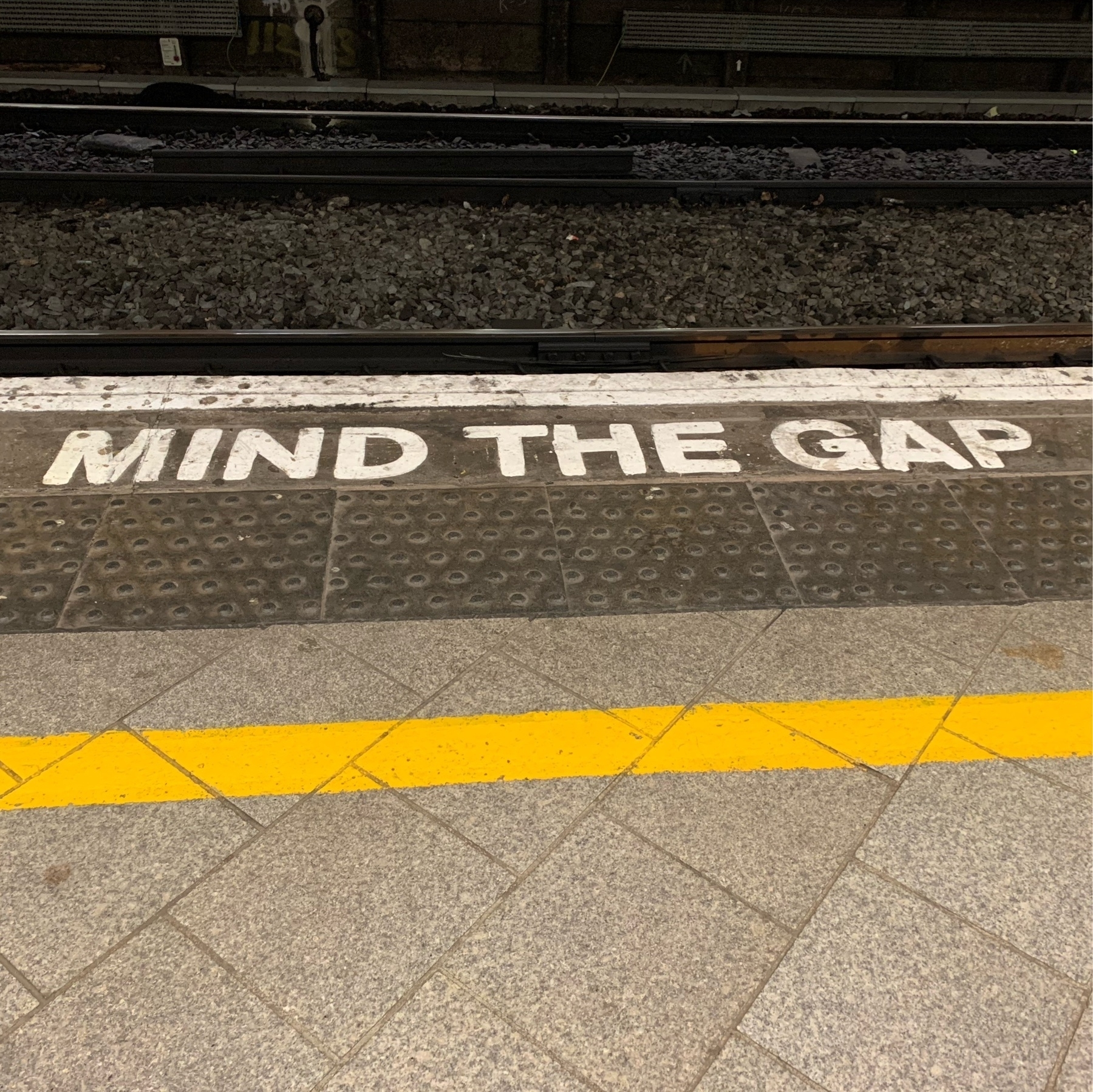 The words "MIND THE GAP" painted on the edge of a railway station platform. 